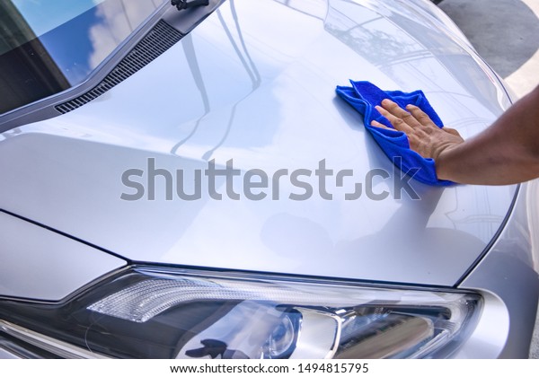 A man\
wiping the car in his hand with a blue\
cloth