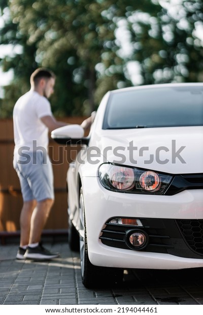 Man is wiping the car with a microfiber\
cloth. Contactless self-service car wash. Personal car care\
cleaning outside. Concept disinfection and antiseptic cleaning of\
vehicle, covid-19 and\
coronavirus