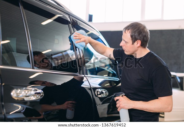 The
man is wiping with a cloth body of a brilliant
car.