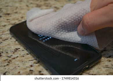 Man Wiping Down His Phone After Being Outside To Protect Against Coronavirus