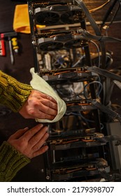 Man Wiping Dust From Cryptocurrency Mining Rig With Rag