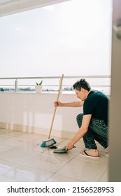 Man Wiping Floor With The Mop. Janitor Washing The Dirty Floors. Guy Mopping The Balcony On A Sunny Day. Person Doing Home Chores. Young Fellow Using Cleaning Equipment To Dust The Surface.