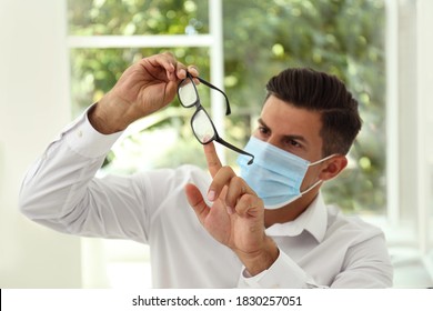 Man Wiping Foggy Glasses Caused By Wearing Medical Mask Indoors