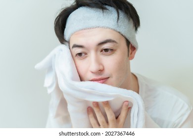 A Man Wiping His Face With A Towel