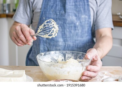 A Man Without A Face In An Apron Holds A Whisk In His Hands And Kneads Dough For Baking In The Kitchen. Authentic Home Cooking Hobby, Home Baker. Man Cooking In The Kitchen At Home