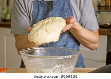 A Man Without A Face In An Apron Holds Raw Bread Dough In His Hands, A Home Baker. Authentic Home Cooking Hobby