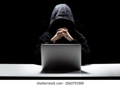 A man without a face behind a laptop, a hacker attack