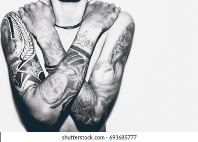 
A man without a shirt, with his hands full of tattoos. 