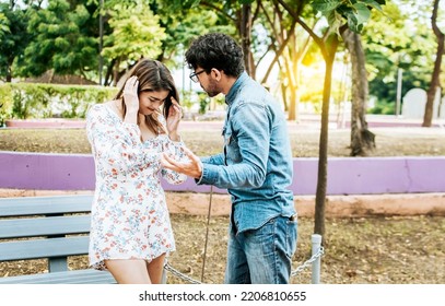 Man And Woman Arguing In A Park. Young Couple Arguing Misunderstanding In A Park, Unhappy Couple Standing Arguing In A Park. Disgusted Teenage Couple Arguing In A Park