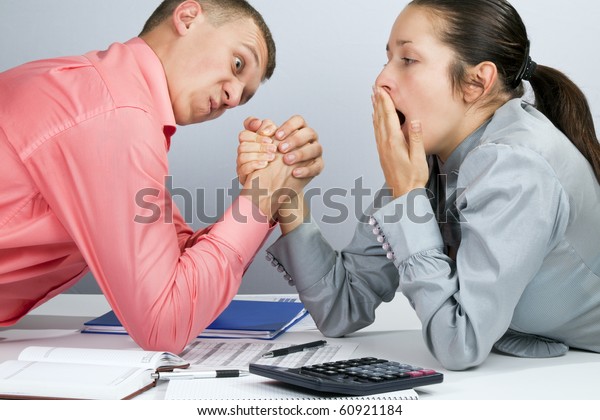 Man and woman in arm wrestling gesture on working\
table during meeting
