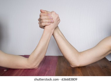 Man And Woman Arm Wrestling On The Table. 