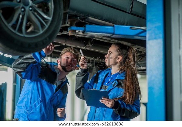 Man\
and woman auto mechanics in a car workshop at\
work