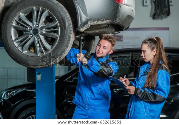 Man\
and woman auto mechanics in a car workshop at\
work