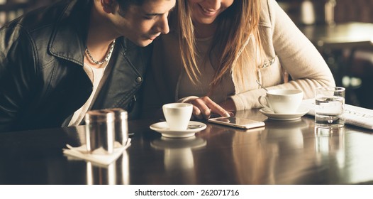 Man And Woman At The Bar Having A Coffee And Using A Mobile Phone