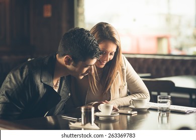 Man And Woman At The Bar Having A Coffee And Using A Mobile Phone