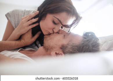 Man And Woman Being Romantic And Kissing. Young Couple In Love On Bed.