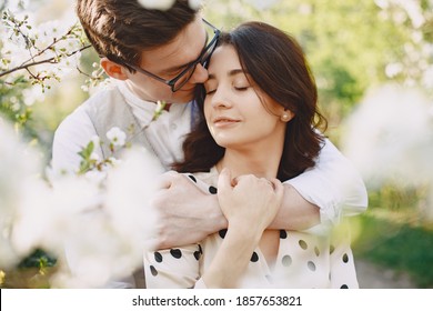 Man And Woman In Blooming Garden On Spring Day. Couple In Love Spend Time In Spring Garden. Flowers On Background.