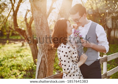 Man and woman in blooming garden on spring day. Couple in love spend time in spring garden. Flowers on background.