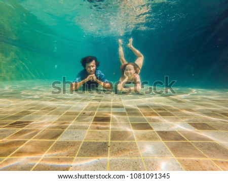 Man and woman at the bottom of the pool, they dive under the water