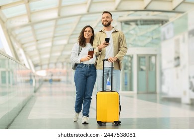 A man and a woman are briskly walking through a busy airport terminal, carrying luggage and looking for their departure gate. - Powered by Shutterstock