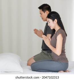 Man And Woman Buddhist Sitting On Bed In The Bedroom And Pay Homage, Praying In Buddhism Religion Style Together. The Idea For Faith And Trust In Religion And Calm Of Mind.