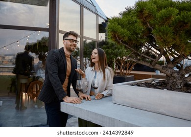 Man and woman business colleagues talking during corporate rooftop party - Powered by Shutterstock