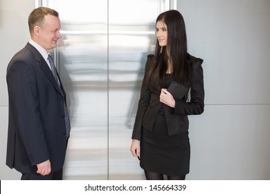 Man And Woman In Business Suits Waiting For Elevator