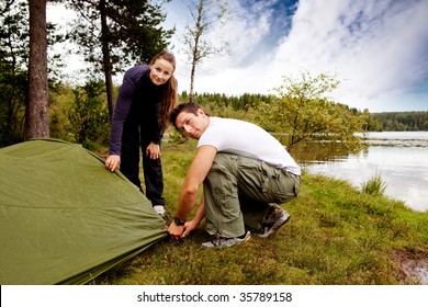 A Man And Woman Camping - Setting Up A Tent