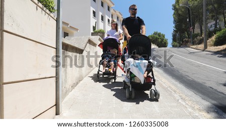A man and a woman carry prams with children on vacation in the summer. Happy family on vacation.