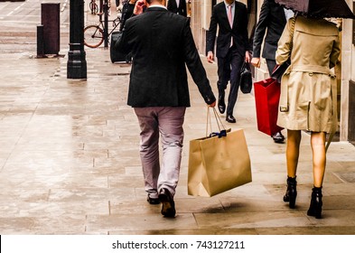 A Man And Woman Carrying Shopping Bags In Luxury Retail Area Of London. 