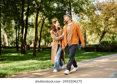 A man and woman in casual attire walk down a peaceful path in a lush park. - Powered by Shutterstock