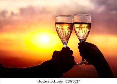 Man and woman clanging wine glasses with champagne at sunset dramatic sky background - Powered by Shutterstock