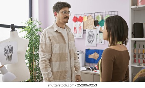 Man and woman collaborating in a bright, modern tailor shop surrounded by fabric samples, sketches, and sewing equipment. - Powered by Shutterstock