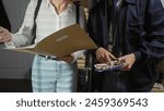 A man and a woman collaborating in a police department, examining evidence and documents indoors.