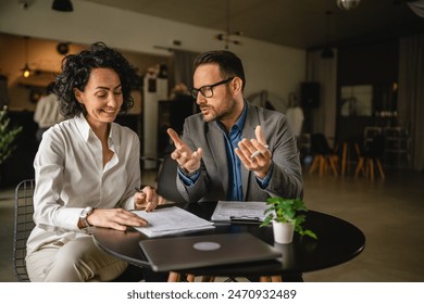 Man and woman colleagues hold and read documents, have discussion and work together at cafe - Powered by Shutterstock