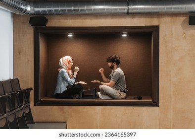 Man and woman comfortably sitting down in a recessed sofa area and playing rock, paper, scissors - Shutterstock ID 2364165397