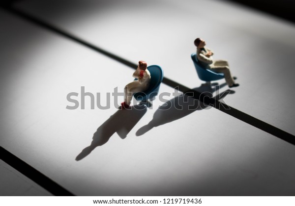 Man and woman in conflict. Divided or divorced\
couple. Two people in need of therapy or counselling. Male and\
female disagreement or argument. Division or separation between the\
genders with shadows.