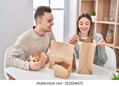 Man And Woman Couple Eating Take Away Food Sitting On Table At Home