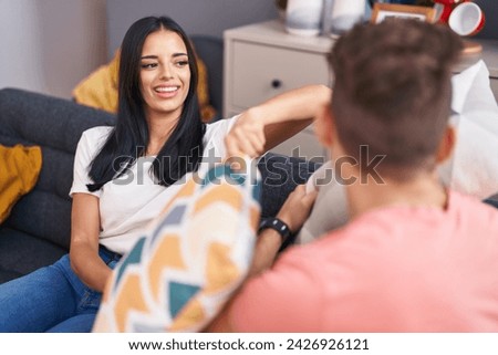 Man and woman couple smiling confident fighting with cushion at home