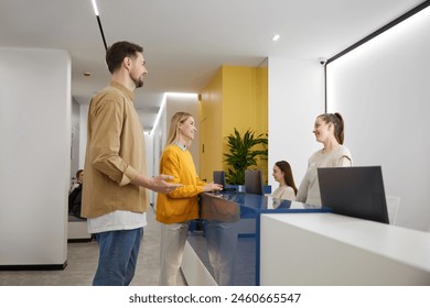 Man and woman couple talking to receptionist at family clinic center - Powered by Shutterstock