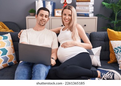 Man and woman couple using laptop expecting baby at home - Powered by Shutterstock