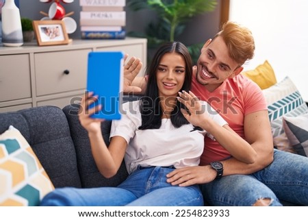 Man and woman couple using touchpad having video call at home