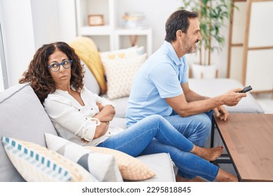 Man and woman couple watching tv sitting on sofa at home - Powered by Shutterstock