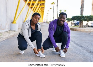 Man and woman couple wearing sportswear tying shoes at street - Powered by Shutterstock