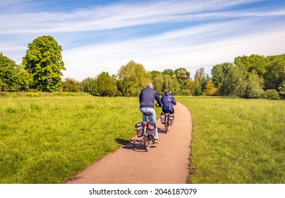 A man and a woman are cycling on a curved bicycle path in a Dutch nature reserve. It is a sunny day in the spring season. - Powered by Shutterstock