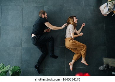 Man and woman depict running while lying on the floor. He's chasing her.