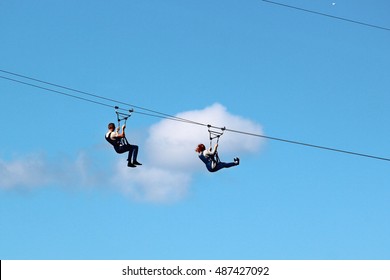 Man And Woman Descend On A Zipline
