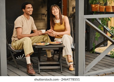 A man and woman of different races are sitting peacefully on a porch, enjoying each others company in a tranquil setting. - Powered by Shutterstock