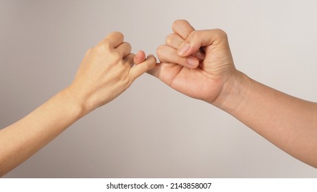 Man and woman do Pinky promise or pinky swear hands sign on white background. - Shutterstock ID 2143858007
