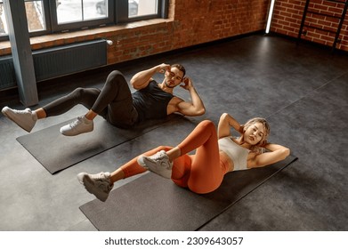Man and woman doing abs exercise at group training class